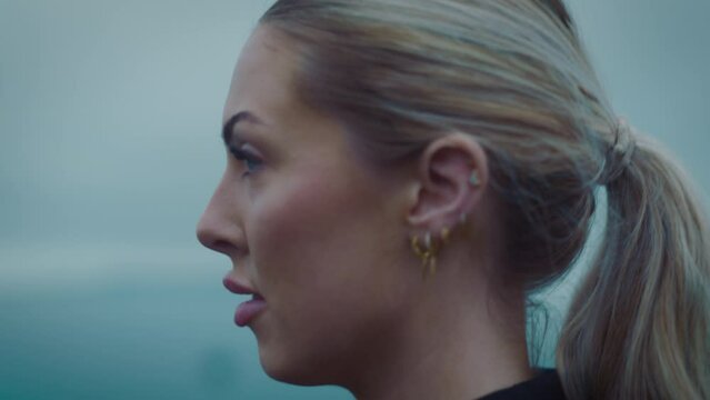 fame walking,  exercising cardio workout training focused female athlete runner in cloudy seaside background tracking close up