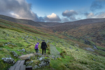 Mother and daughter walking on a trail in Glendalough with a view on a valley and stream. Hiking in...