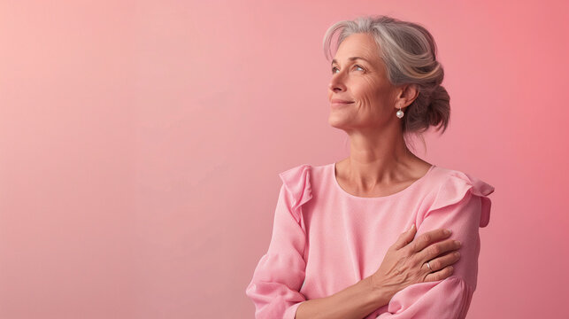 Retrato de mujer madura vestida de color rosa sobre fondo liso de color rosa. 