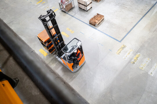 fahrender Reach Truck bzw. Schubmaststapler / Gabelstapler im Logistik-Lager mit Rollregal 