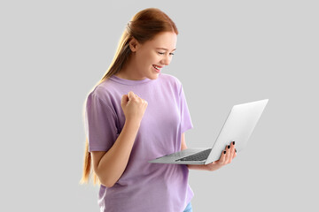 Happy female programmer with laptop on light background