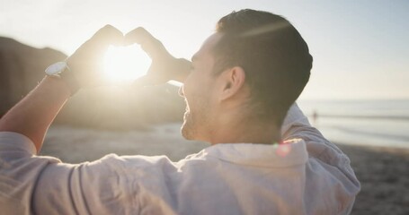 Man, heart hands and happy on beach with sunset for romance, holiday or vacation outdoor in nature. Person, travel and emoji with sunrise for adventure, scenery and view with freedom and lens flare - Powered by Adobe
