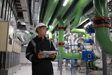Fototapeta na wymiar Mechanical Engineer using a digital tablet to Examine the Pipeline system of cooling installation