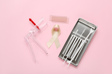 Beige ribbon with gynecological tools on pink background. Uterine cancer awareness concept