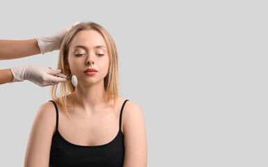 Fototapeta premium Young woman receiving facial massage on grey background