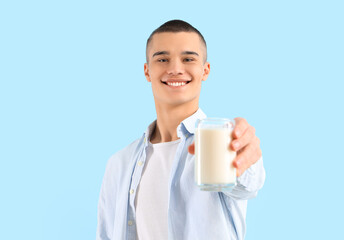 Teenage boy with glass of milk on blue background