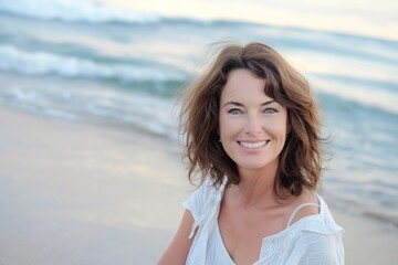 Fototapeta na wymiar Smiling attractive beautiful caucasian mature woman posing at the beach looking at the camera