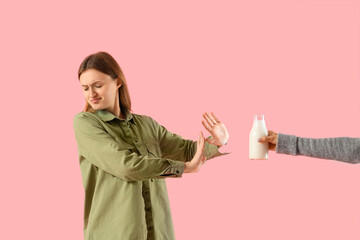 Displeased woman with lactose intolerance rejecting milk on pink background