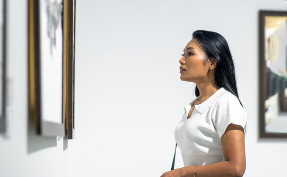 A young woman looks at paintings at an exhibition