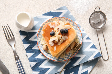 Plate with tasty pancakes in shape of heart, blueberry, nuts and milk on light background. Valentine's Day celebration