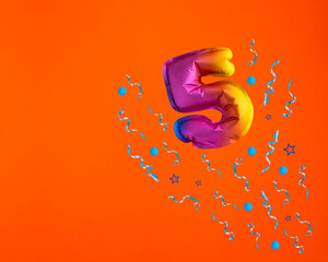 Multicolor balloon number 5 - Confetti explosion on orange background. Birthday card