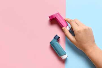 Child's hand with asthma inhalers on color background