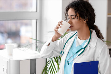 Female African-American medical intern drinking water in clinic