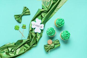 Tasty cupcakes with gift box, cloth and festive postcard for St. Patrick's Day on turquoise...