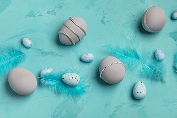 Easter eggs with feathers on turquoise grunge background