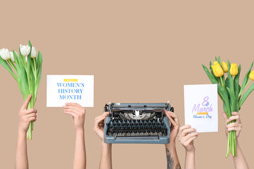 Hands holding vintage typewriter with tulips and festive postcards on beige background. Women's Day...