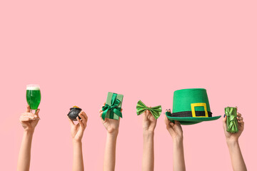 Female hands holding beer and party decor for St. Patrick's Day celebration on pink background - obrazy, fototapety, plakaty