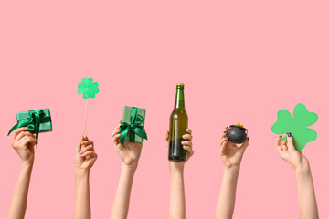 Female hands holding beer and party decor for St. Patrick's Day celebration on pink background