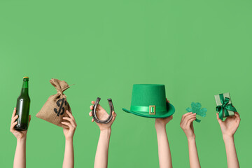 Female hands holding beer and party decor for St. Patrick's Day celebration on green background