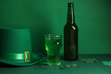 Glass and bottle of beer with leprechaun hat on green background. St. Patrick's Day celebration
