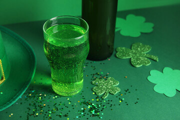 Glass and bottle of beer with clover on green background. St. Patrick's Day celebration