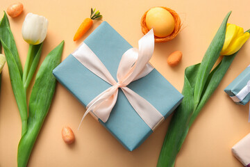 Easter eggs with tulip flowers and gift box on orange background