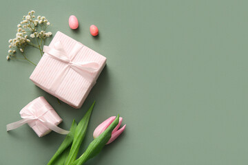 Easter eggs with gift boxes and tulip flower on green background