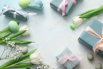 Frame made of Easter eggs with flowers and gift boxes on blue grunge background