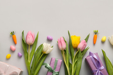 Easter eggs with tulip flowers and gift boxes on grey background