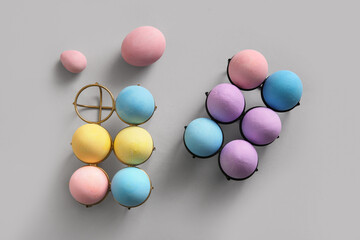 Holders with painted Easter eggs on grey background