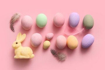 Painted Easter eggs with feathers and bunny on pink background