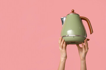 Woman with electric kettle on pink background