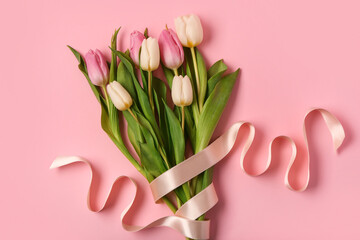 Beautiful tulips with ribbon on pink background. International Women's Day
