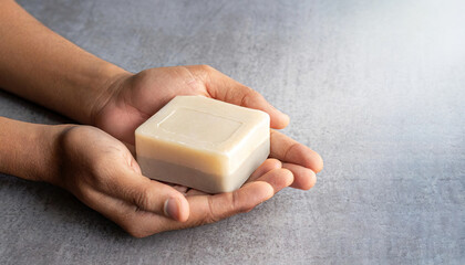 Hands Holding a Soap on Gray Background, Emphasizing the Importance of Daily Hygiene and Self-care - Horizontal