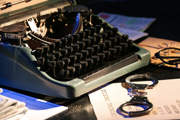 Retro typewriter, handcuffs and criminal files on dark table, closeup