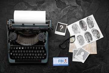 Retro typewriter, eyeglasses, fingerprints and document of FBI agent on dark background