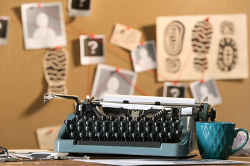 Retro typewriter and cup of tea on table against crime board