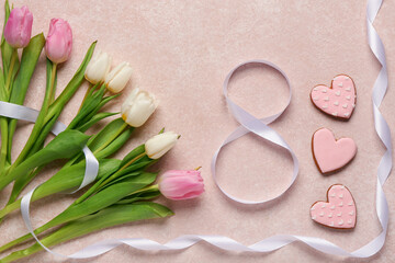 Figure 8 made of ribbon with tulip flowers and cookies on pink grunge background. International Women's Day celebration