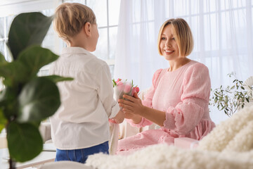 Obraz na płótnie Canvas Happy mother receiving tulips from her little son at home. International Women's Day