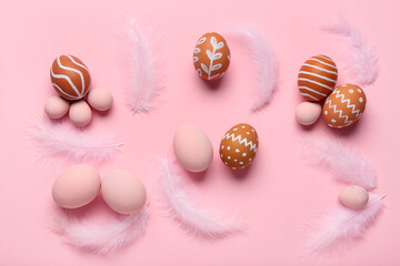 Composition with painted Easter eggs and feathers on pink background