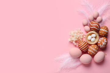 Composition with painted Easter eggs, nest and feathers on pink background