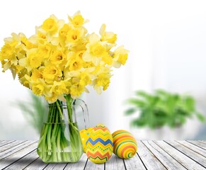 Easter eggs and yellow flower on room background.