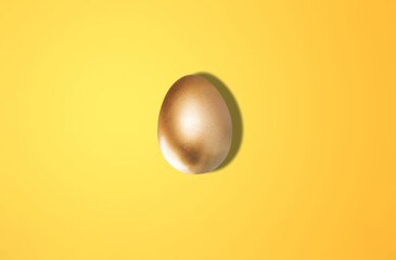 Gold egg on the yellow background in center.  art minimalism Easter concept