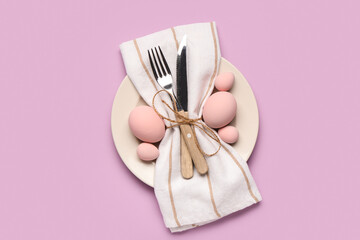 Beautiful table setting with Easter eggs, napkin and cutlery on purple background