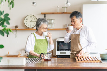 キッチンでコーヒーを飲むアジア人高齢者夫婦（笑顔）
