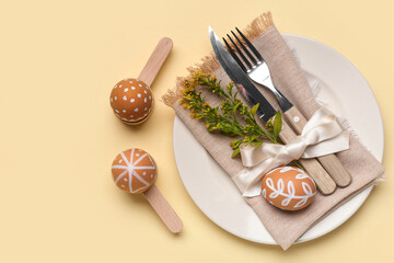 Beautiful table setting with Easter eggs, napkin and cutlery on yellow background