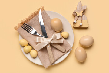 Stylish table setting with Easter eggs, napkin and cutlery on yellow background