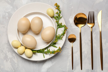 Beautiful table setting with Easter eggs, flowers and cutlery on grunge grey background