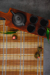 Black teapot and cups with bamboo leaves on a tray. Traditional tea ceremony.