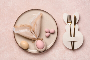 Stylish table setting with Easter eggs, paper bunny, napkin and cutlery on pink grunge background